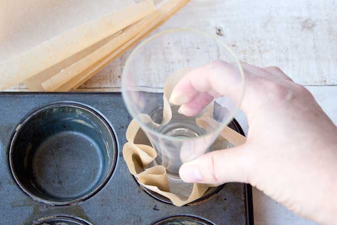 Forming a muffin liner out of parchment paper.