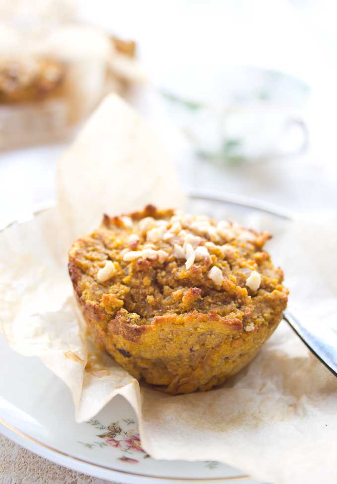 a pumpkin muffin topped with hazelnuts on a plate 