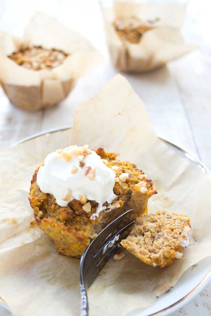 A keto pumpkin muffin on a plate with cream and a fork.