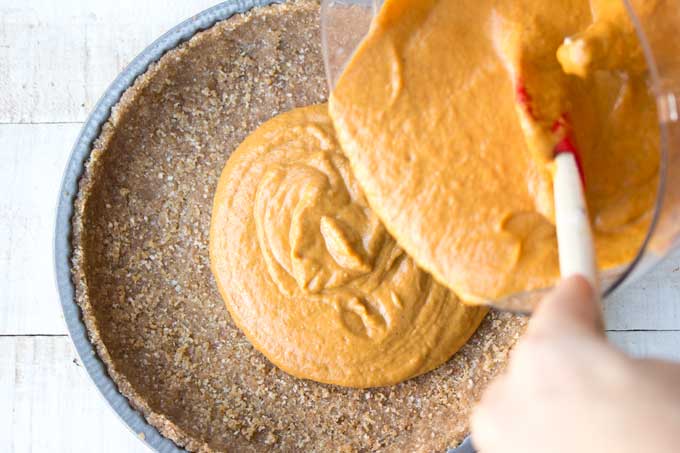 pouring pumpkin filling onto a pie crust