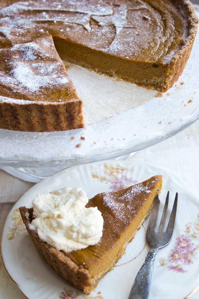 A pumpkin pie and a slice of pumpkin pie on a plate.