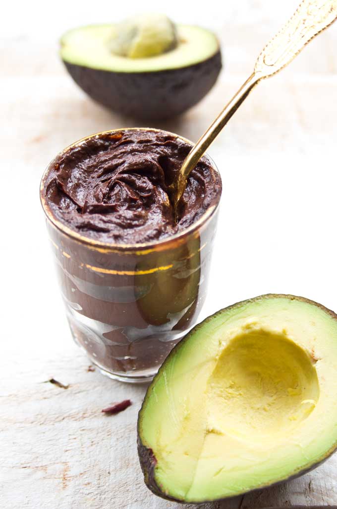 a glass with chocolate avocado mousse and avocados