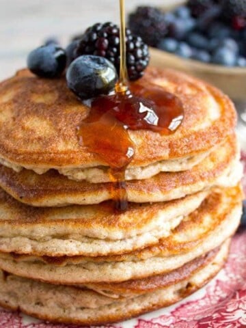 a stack of pancakes decorated with berries and sugar free syrup drizzle