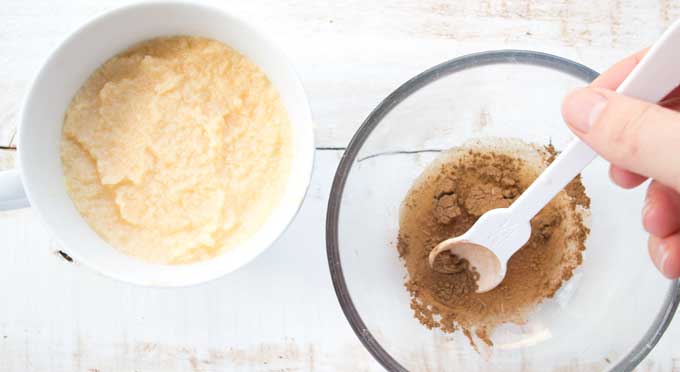 Stirring the cinnamon swirl sauce in a bowl with a spoon and a mug with an unbaked coconut flour mug cake