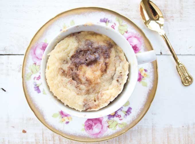 A coconut flour mug cake in a mug and a spoon on the side