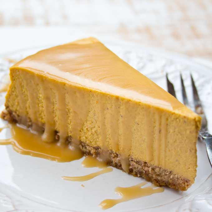 A slice of sugar free pumpkin cheesecake with caramel sauce on a plate. 