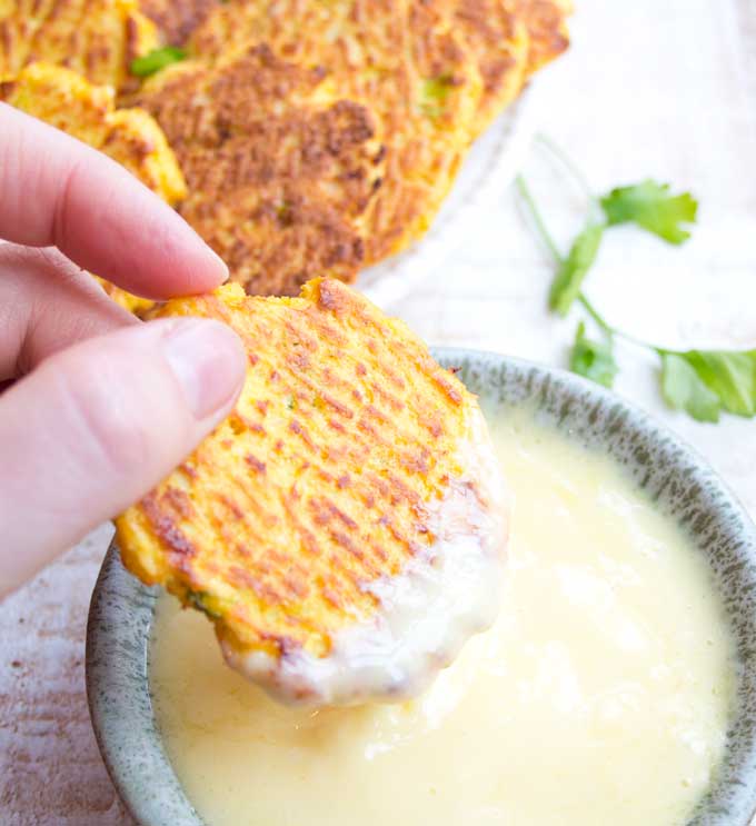 dipping a cauliflower hash brown into a bowl with mayonnaise