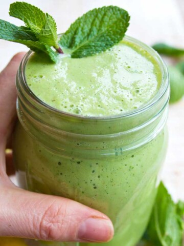 hand holding a glass of keto green smoothie