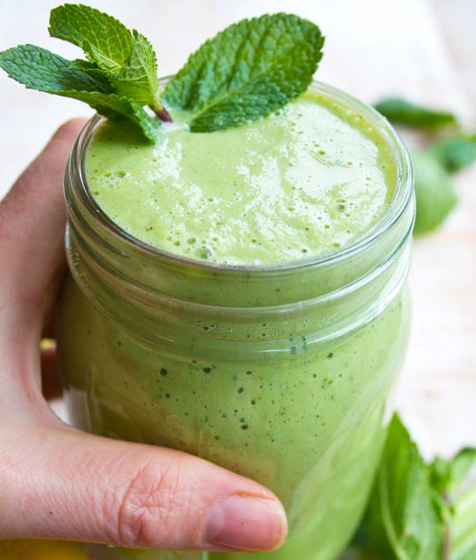 hand holding a glass of green smoothie