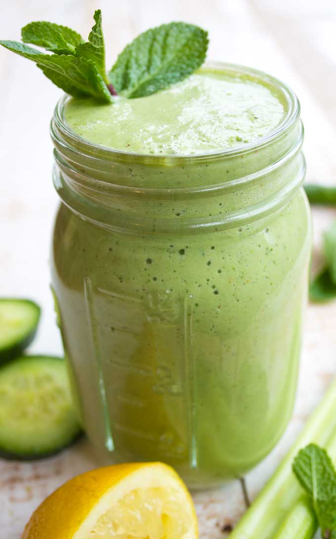 a glass of green smoothie decorated with mint leaves