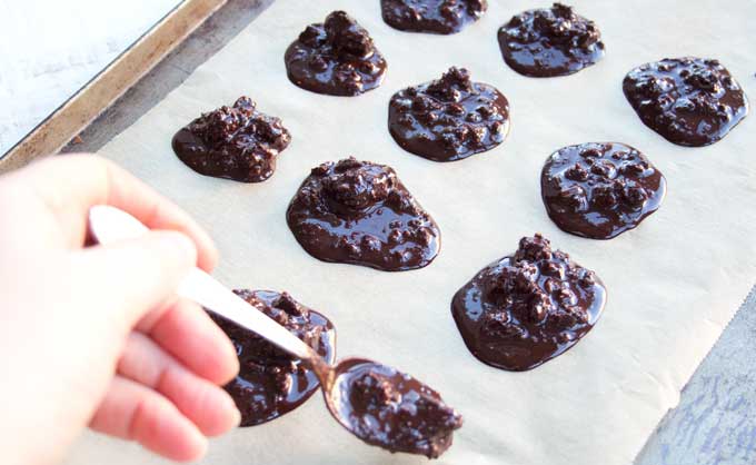 spooning low carb chocolate onto a baking sheet lined with parchment paper 