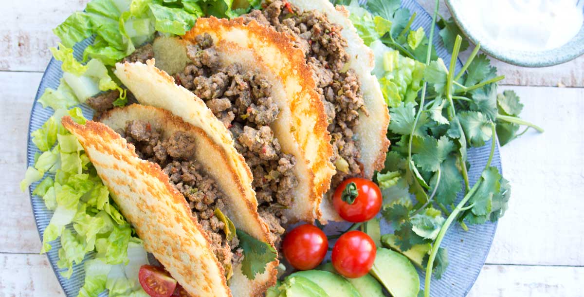 3 keto taco shells filled with taco meat on a salad bed