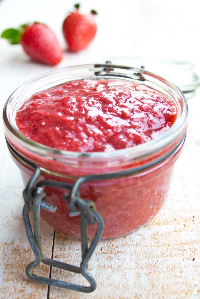 an open jar with sugar free strawberry jam and 2 strawberries