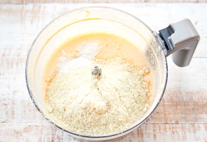 adding almond flour to the Keto lemon bar batter inside a food processor bowl