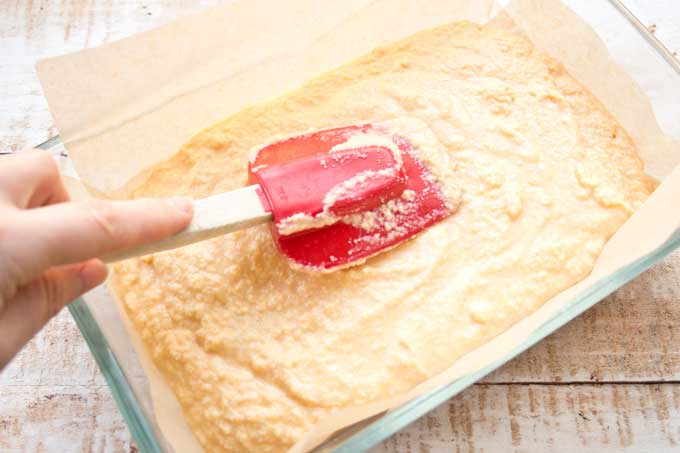 smoothing the batter for Keto lemon bars in a rectangular baking pan with a spatula