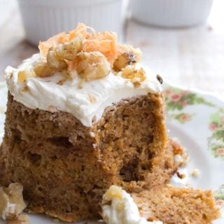 microwave keto carrot cake topped with cream cheese frosting on a plate with a spoon taking off a piece