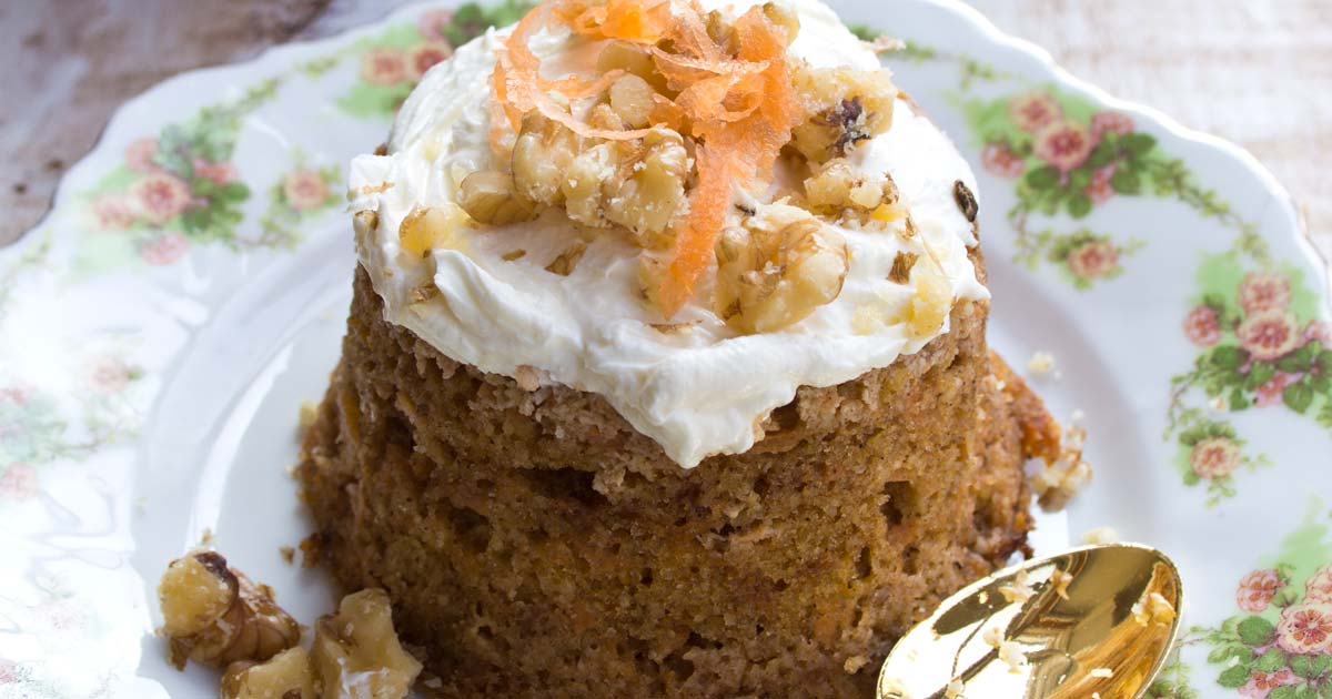 a keto carrot mug cake with cream cheese frosting on a plate with a spoon