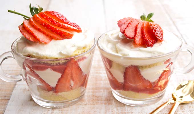two glass coffee cups filled with homemade strawberry shortcake trifle