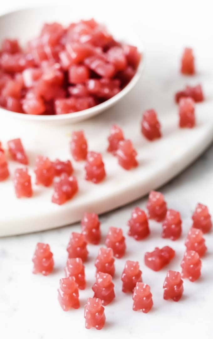 a little army of triple berry keto gummy bears in a bowl and on a table