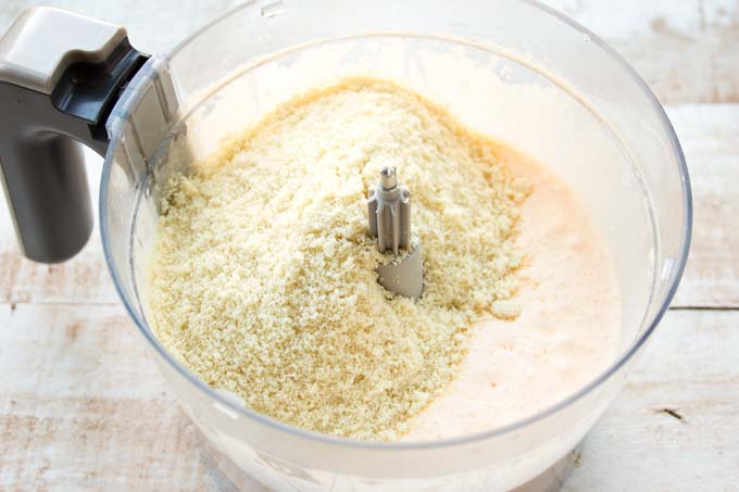 wet ingredients such as frothed eggs and almond flour in a food processor bowl