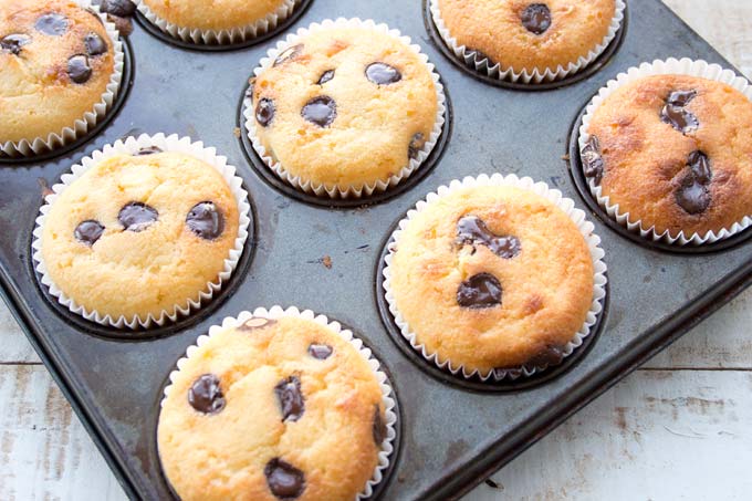 a muffin tray with baked chocolate chip muffinss