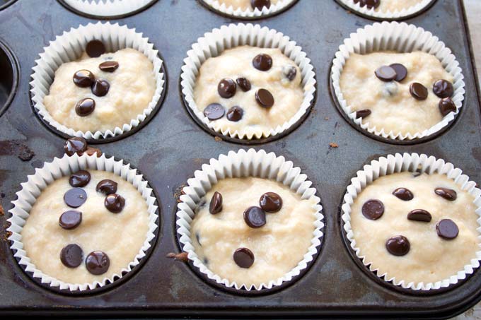chocolate chip muffin batter in white paper cases in a baking tray