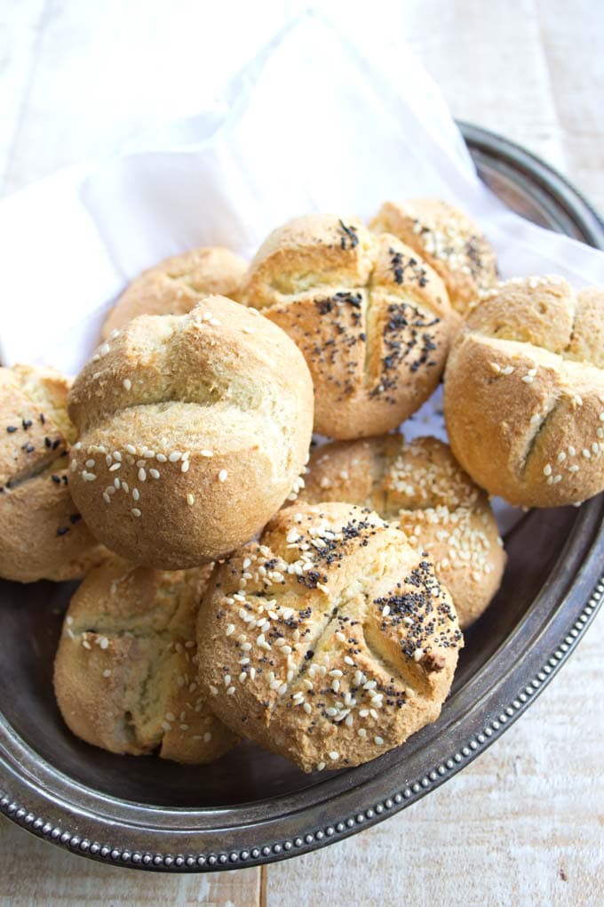 A silver tray with baked Keto dinner rolls topped with a mix of poppy seeds and sesame seeds
