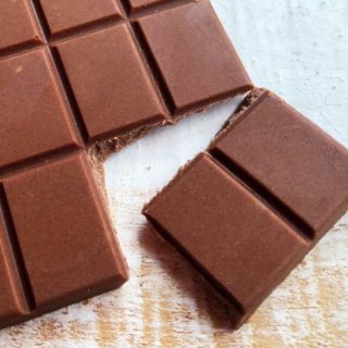 closeup of two pieces of keto milk chocolate tha have been broken off from a bar of homemade sugar free chocolate