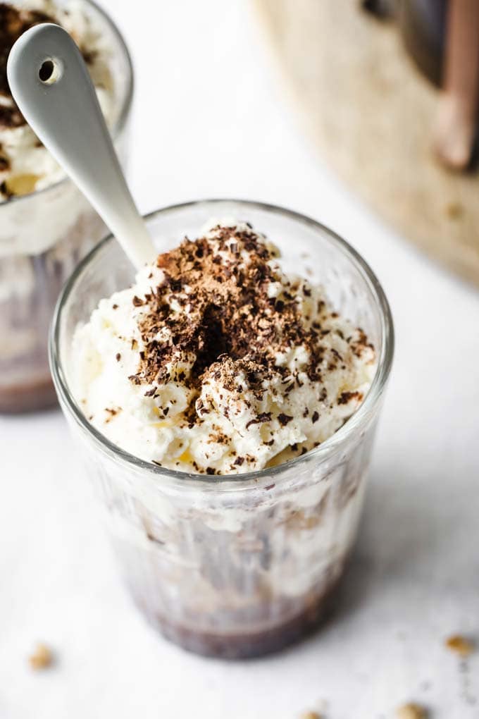 view looking down onto a glass filled with tiramisu and topped with chocolate shavings and a spoon