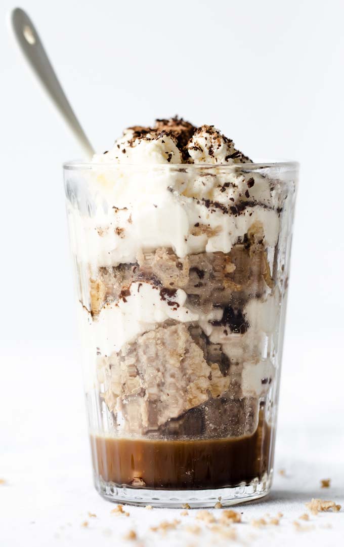 a glass with homemade tiramisu showing two layers of coffee-soaked sponge cake and mascarpone and a spoon