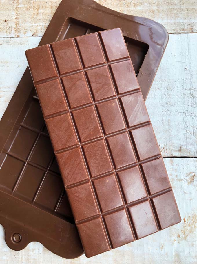 a bar of keto milk chocolate with a brown silicone chocolate mould beneath on a table