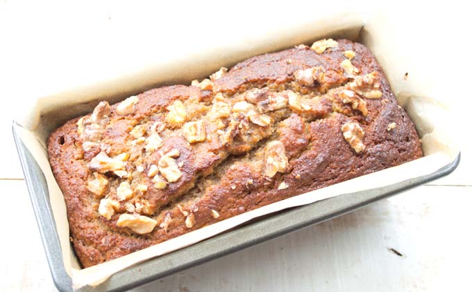 baked low carb banana bread topped with crushed walnuts in a bread tin