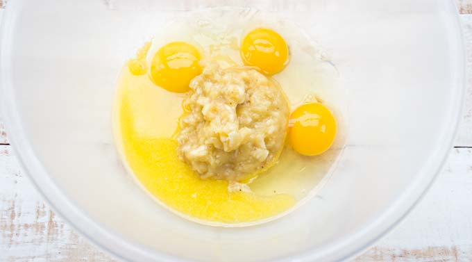 a bowl with mashed banana, eggs and melted butter