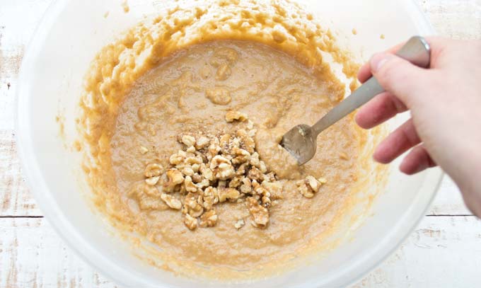 banana bread dough with crushed walnuts in a bowl and a fork