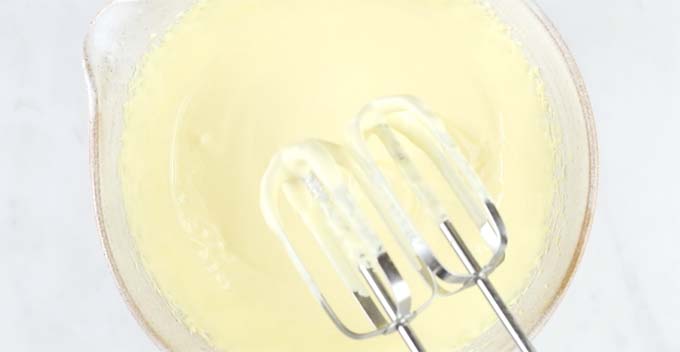 Egg yolks and sweetener being beaten in a bowl with an electric mixer