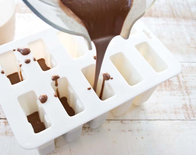 pouring chocolate peanut butter mix in a white ice cream mold