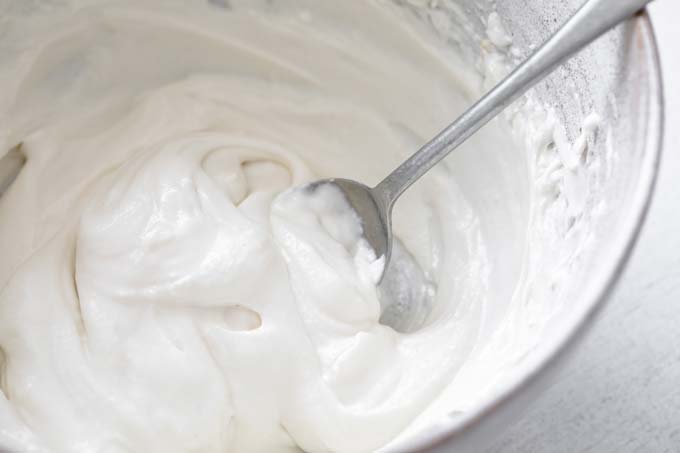 mascarpone and coconut cream mix in a bowl with a spoon