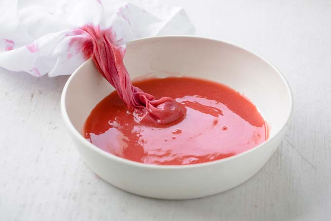 strawberry juice with a muslin cloth in a bowl