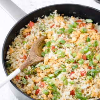 Closeup of cauliflower fried rice with spring onions and pepper in a cast iron pan