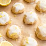 Keto lemon cookies with a lemon glaze and sprinkled with zest on a sheet of baking paper and lemon halves