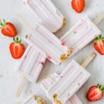 strawberry cheesecake popsicles on a wooden surface