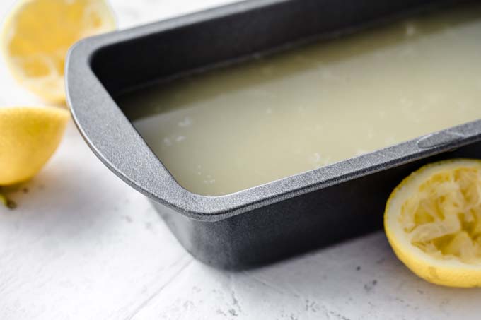 lemon syrup in a loaf tin and lemon halves 