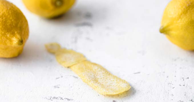 lemon peel on a white table with lemons in the background