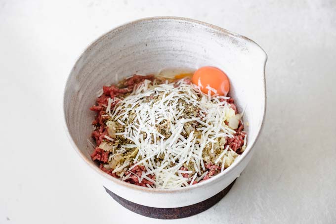 beef mince, egg, onions and herbs in a bowl