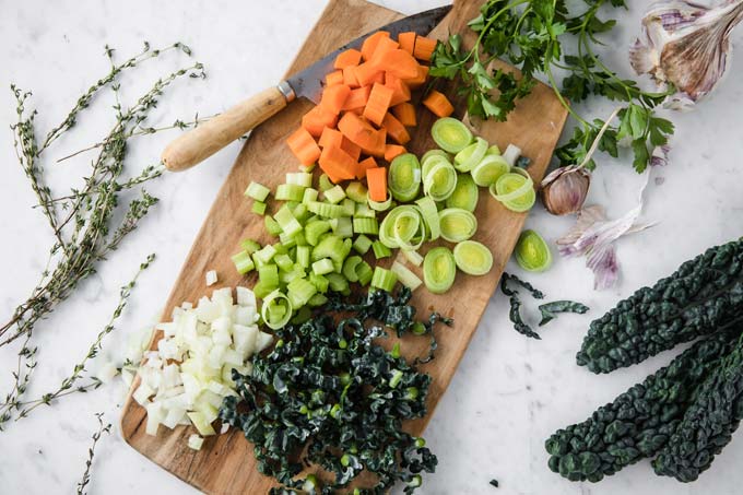 Chopped vegetables on a wooden board and a knife.