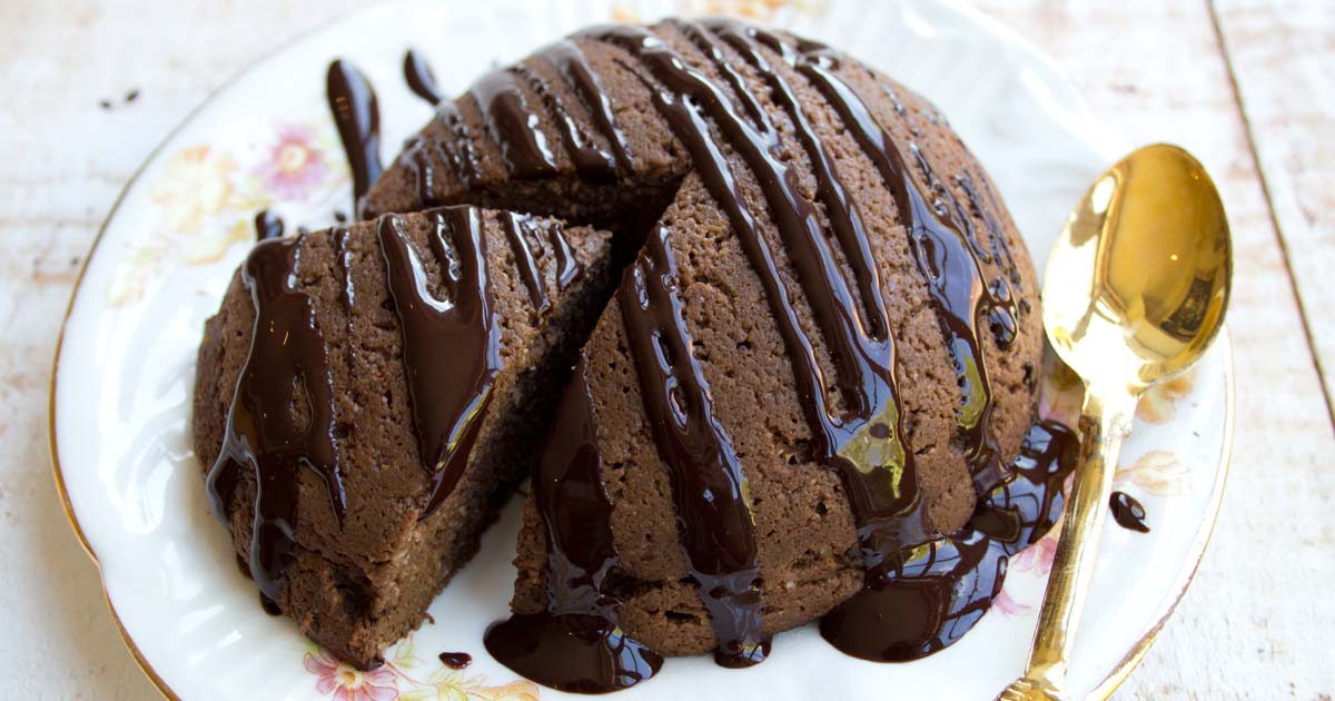 a round chocolate pumpkin cake on a plate and a spoon