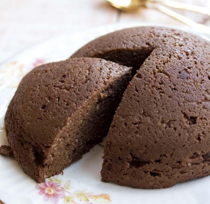 A round mini chocolate pumpkin cake on a plate with a slice being removed.