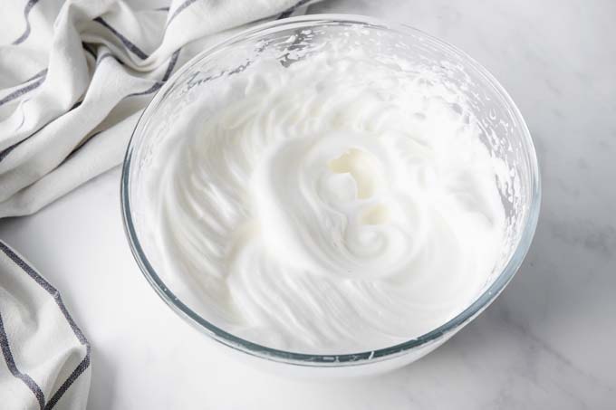 Whipped egg whites in a glass bowl.