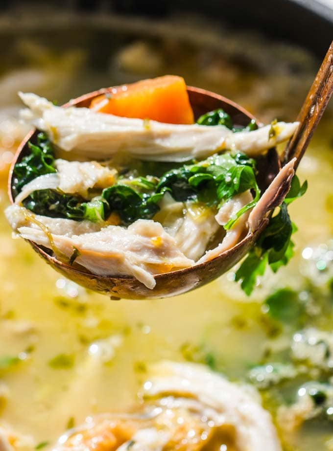 Closeup of a ladle with chicken soup.