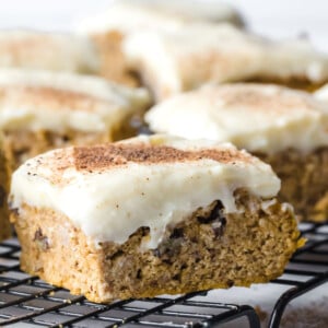 Pumpkin bars with cream cheese frosting on a baking rack.